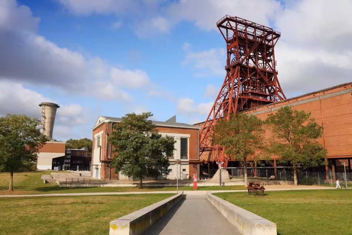 Industriedenkmal mit Fördergerüst und Gebäude im Grünen.