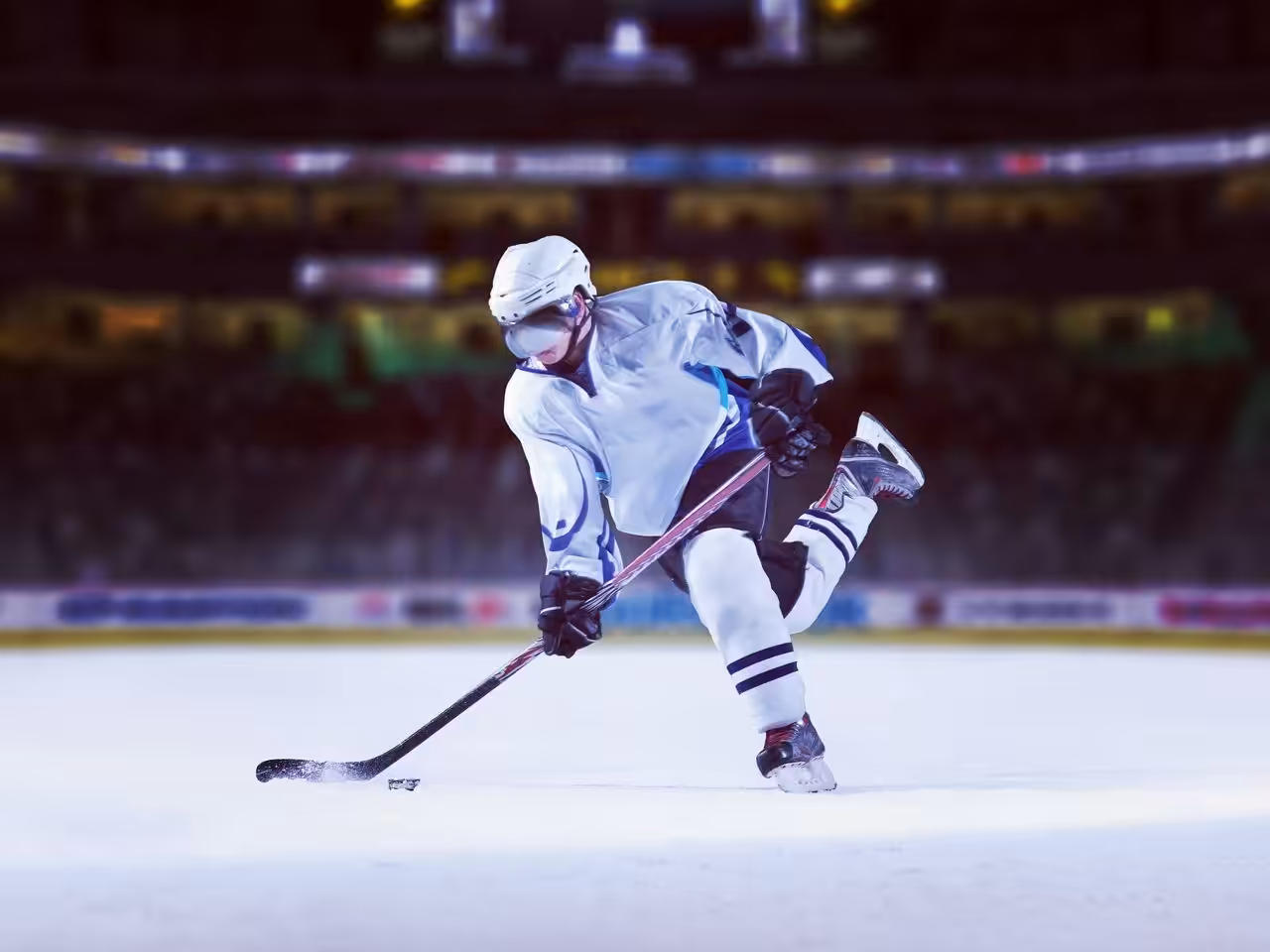 Eishockeyspieler schießt den Puck auf dem Spielfeld.