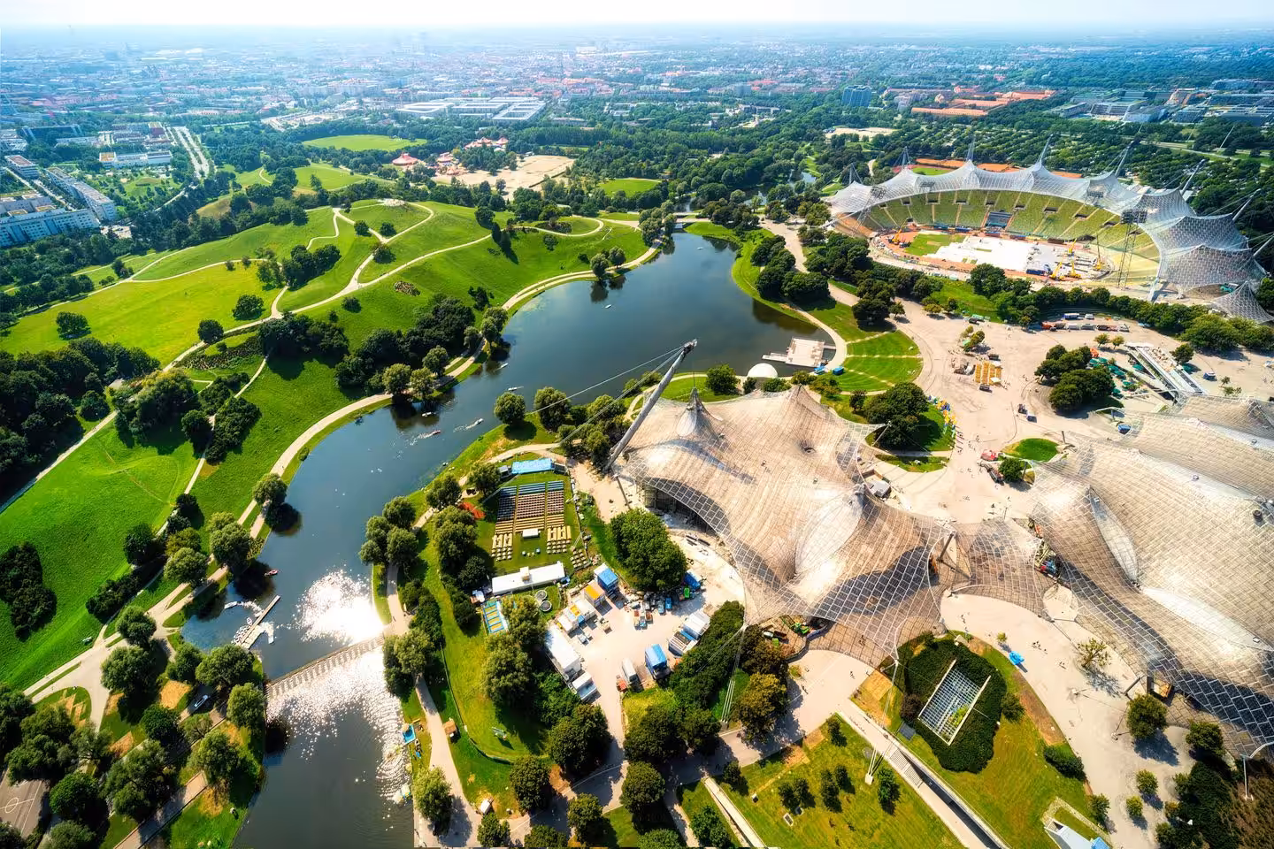 Luftaufnahme Olympiapark München mit Grünflächen und Wasserflächen.