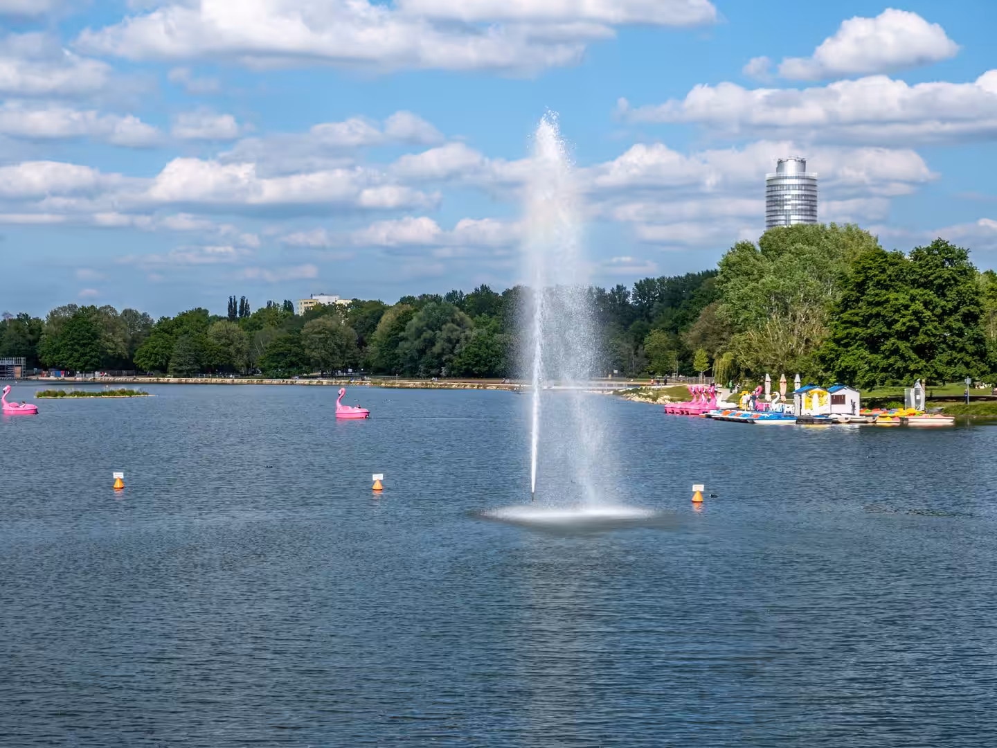 See mit Fontäne und rosa Tretbooten im Sommer.
