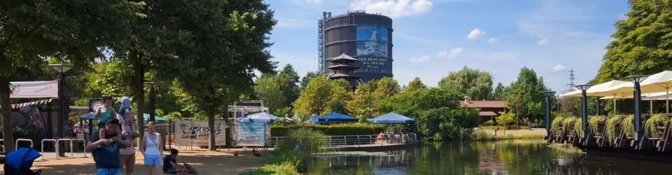 Gasometer im Park mit Spaziergängern.